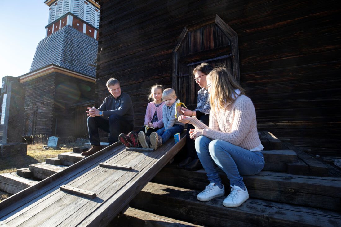 ihmisiä syömässä eväitä Petäjäveden vanhan kirkon portailla